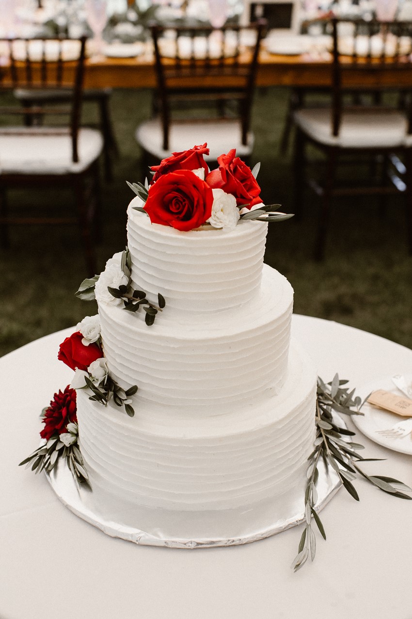 White Wedding Cake Topped with Red Flowers